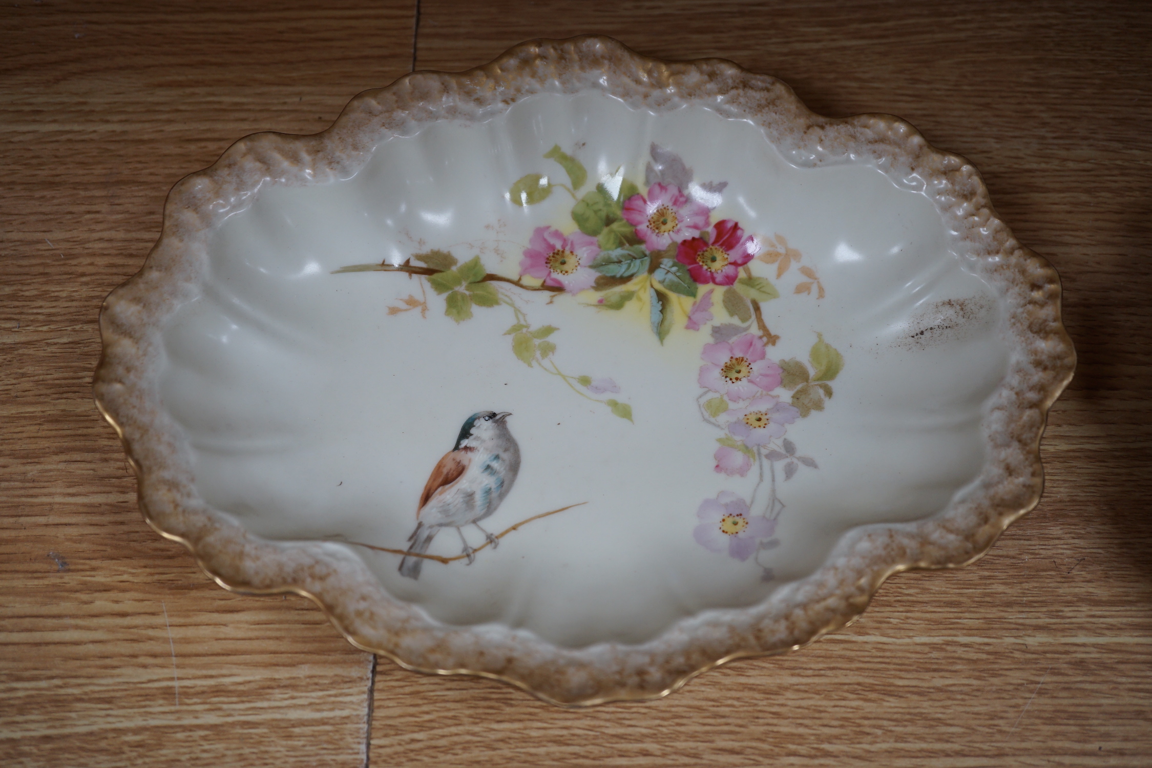 A Limoges dessert service decorated with birds and flowers, the largest 27cm wide